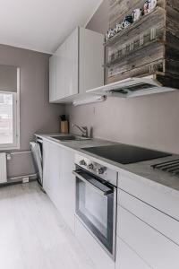 Una cocina con gabinetes blancos y un horno de estufa. en SleepWell House Pyhätunturi with Sauna close to lake, en Pelkosenniemi
