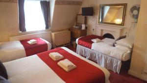 una camera d'albergo con due letti e uno specchio di Arran House Hotel a Londra