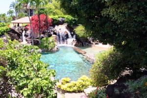 a small pool with a waterfall in a garden at Hanalei Bay Resort 7302 in Princeville