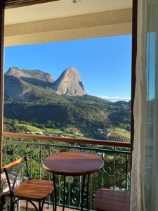 uma varanda com uma mesa e cadeiras e uma montanha em Apart Pedra Azul em Pedra Azul