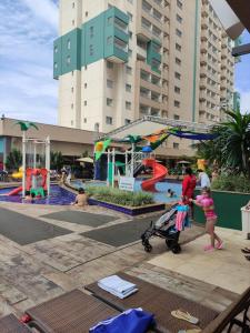 une femme et un enfant avec une poussette dans une aire de jeux dans l'établissement Apartamento em Olímpia, à Olímpia