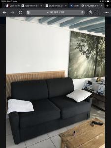 een woonkamer met een zwarte bank en een tafel bij Studio coeur de Luc/Mer in Luc-sur-Mer