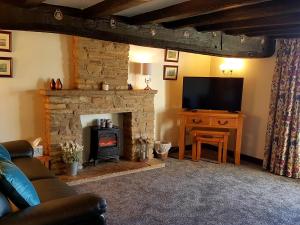 uma sala de estar com lareira e televisão em Wethercote Cottage em Cold Kirby