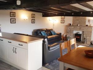 a living room with a leather couch and a table at Wethercote Cottage in Cold Kirby