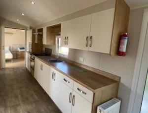 a kitchen with white cabinets and a counter top at Emma's Escape accessible caravan at Durdle Door in West Lulworth