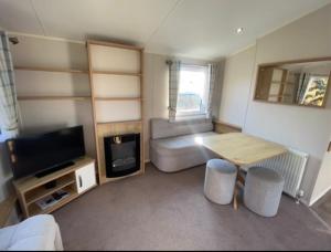 een kleine woonkamer met een tafel en een televisie bij Emma's Escape accessible caravan at Durdle Door in West Lulworth