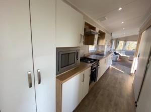 a kitchen with white cabinets and a stove top oven at Emma's Escape accessible caravan at Durdle Door in West Lulworth