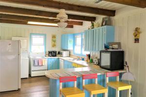 une cuisine avec des placards bleus et un comptoir avec des tabourets dans l'établissement The Ocean Rose, à Île au chêne