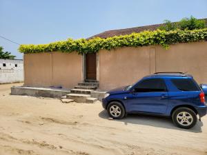 a blue car parked in front of a house at ROMO house in Cotonou