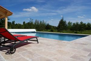 a red chair sitting next to a swimming pool at Chateau De Grenier Apartment in Saint-Léger