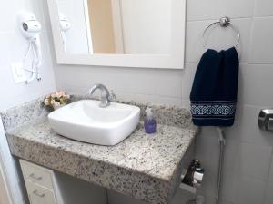eine Badezimmertheke mit einem Waschbecken und einem Spiegel in der Unterkunft Conforto a 300m da Praia do Forte in Cabo Frio