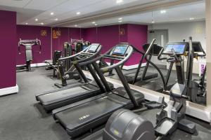 une salle de sport avec plusieurs machines à bande de roulement dans un mur violet dans l'établissement YOTEL London City, à Londres