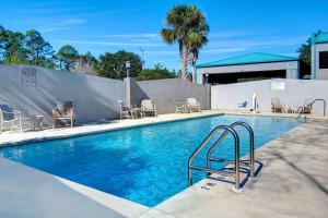 uma piscina com cadeiras e uma cerca em Studio 6 Pensacola, FL - West I-10 em Pensacola