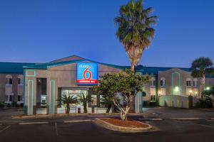 a hotel with a palm tree in front of a building at Studio 6 Pensacola, FL - West I-10 in Pensacola