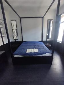 a bedroom with a bed with a blue comforter and two windows at B96 suites in Brussels