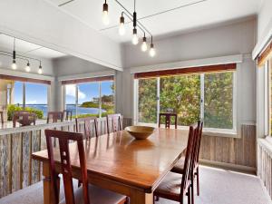 une salle à manger avec une table et des chaises en bois dans l'établissement The Beach House Gerroa, à Gerroa