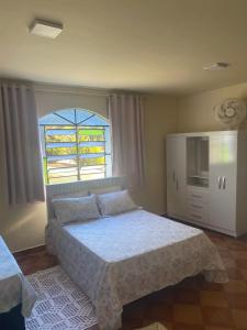 a bedroom with a large bed and a window at Casa com Flores in Pedra Azul