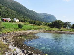 a river in a field with a house and mountains at 6 person holiday home in FISK in Fiskå