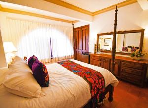 a bedroom with a bed with a mirror and a dresser at Collection O Casa Bella Hotel Boutique, Cabo San Lucas in Cabo San Lucas