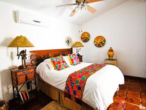 1 dormitorio con 1 cama con almohadas coloridas y ventilador de techo en Collection O Casa Bella Hotel Boutique, Cabo San Lucas en Cabo San Lucas