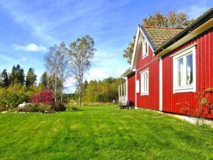 una casa roja con un césped verde al lado en 4 person holiday home in Br landa en Brålanda