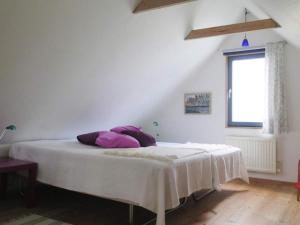 a white bed with purple pillows in a room at 2 person holiday home in Garsnäs-By Traum in Gärsnäs
