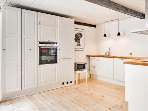 een keuken met witte kasten en houten vloeren bij 5 person holiday home in Aakirkeby in Åkirkeby