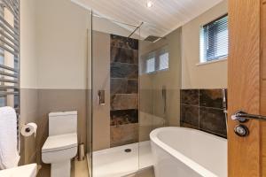 a bathroom with a tub and a toilet and a sink at Ael-Y-Bryn - Luxury Lodge, Hot Tub, Three En-Suite Bedrooms in Penally +10 photos