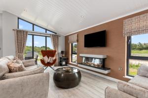 a living room with a fireplace and a tv at Ael-Y-Bryn - Luxury Lodge, Hot Tub, Three En-Suite Bedrooms in Penally