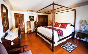 - une chambre avec un lit à baldaquin et une chaise dans l'établissement Collection O Casa Bella Hotel Boutique, Cabo San Lucas, à Cabo San Lucas