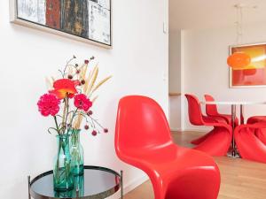 une chaise rouge et un vase avec des fleurs sur une table dans l'établissement 6 person holiday home in Skagen, à Skagen