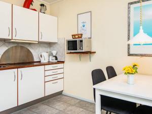 a kitchen with white cabinets and a table and a microwave at 4 person holiday home in Rømø-By Traum in Sønderby +36 photos
