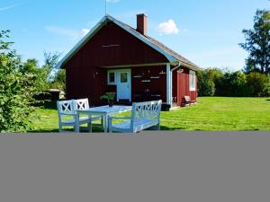 a red barn with two white benches in front of it at 5 person holiday home in F RJESTADEN in Färjestaden