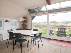 ein Esszimmer mit einem Tisch und Stühlen sowie einem großen Fenster in der Unterkunft 6 person holiday home in Pandrup in Rødhus