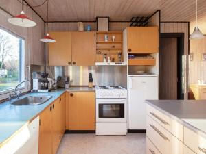 cocina con armarios de madera y horno de fogón blanco en 6 person holiday home in V ggerl se, en Bøtø By
