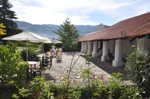 eine Terrasse mit Tischen und Sonnenschirmen neben einem Gebäude in der Unterkunft Estancia Las Tacanas in Tafí del Valle