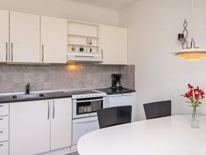een keuken met witte kasten en een tafel met stoelen bij 4 person holiday home in R m in Sønderby