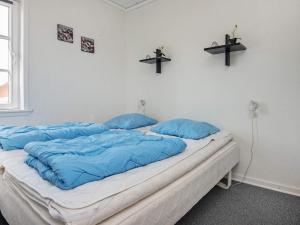 een bed met blauwe kussens in een kamer bij 4 person holiday home in R m in Sønderby