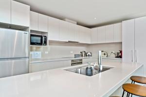uma cozinha branca com um lavatório e um frigorífico em Two Views Taupo Apartment em Taupo