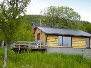 una casa amarilla con un porche en un campo en 5 person holiday home in Straumsbukta en Bakke