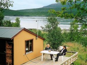 dos personas sentadas en una mesa en una cubierta en 5 person holiday home in Straumsbukta en Bakke