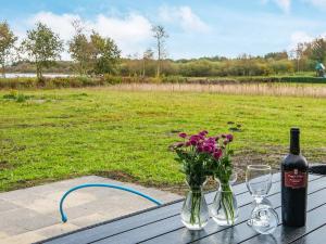 8 person holiday home in Ansager في Ansager: طاولة مع زجاجة من النبيذ و إناء من الزهور