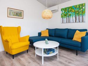 a living room with a blue couch and two yellow chairs at 8 person holiday home in Ansager in Ansager