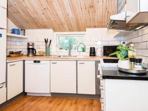 kuchnia z białymi szafkami i drewnianym sufitem w obiekcie 8 person holiday home in Juelsminde w mieście Sønderby