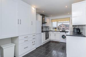 a kitchen with white cabinets and a tile floor at FW Haute Apartments at Stanmore, 3 Bedrooms and 1 Bathroom with additional WC, Single or Double Beds, Pet Friendly Flat with FREE WIFI and FREE PARKING in Stanmore