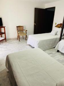 a hotel room with two beds and a chair at Hostal Guadalajara Cosmopolitan Providencia in Guadalajara