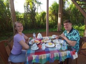 un hombre y una mujer sentados en una mesa con comida en Sigiriya Paddy Field Hut, en Sigiriya