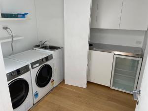 a kitchen with a washing machine and a sink at LUXURIOUS WATERFRONT Home in Nelson