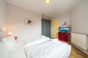 ein Schlafzimmer mit einem großen weißen Bett und einem Flachbildfernseher in der Unterkunft Hus Inselkieker Hus Inselkieker 425 in Schillig
