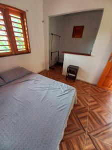Schlafzimmer mit einem Bett und Holzboden in der Unterkunft CASINHA DA SERRA in Baturité